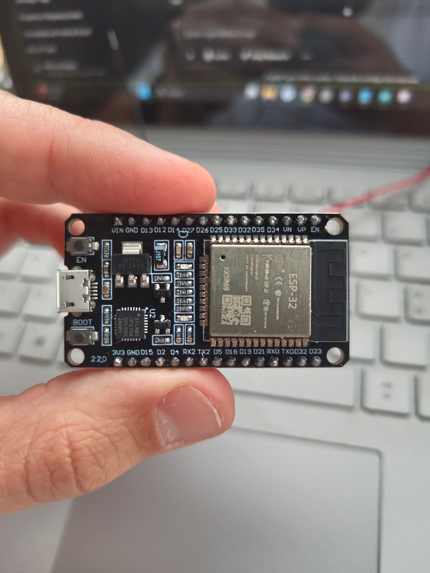 ESP32 dev board held in front of the firmware on screen